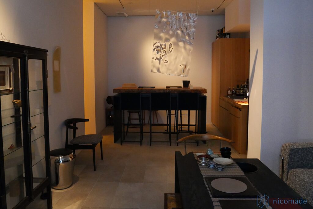 黒い格子のガラス棚とハイカウンター、ダイニングテーブルを置いた落ち着いた照明の店内