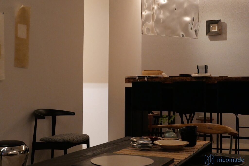 布張りの椅子と黒いカウンター、器を並べたテーブルのある店内